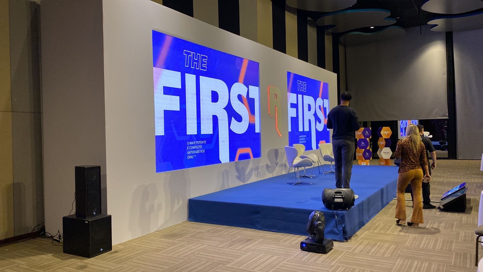 Fundo de palco em SMX com lona impressa, letra caixa iluminada e tablado azul durante a montagem